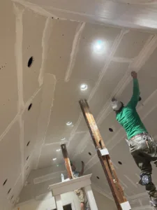 Workers performing drywall ceiling finishing with joint compound.