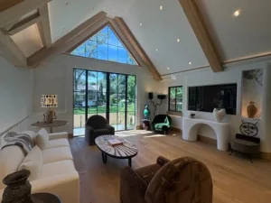 Modern interior painting in a bright living room with vaulted ceiling and large windows