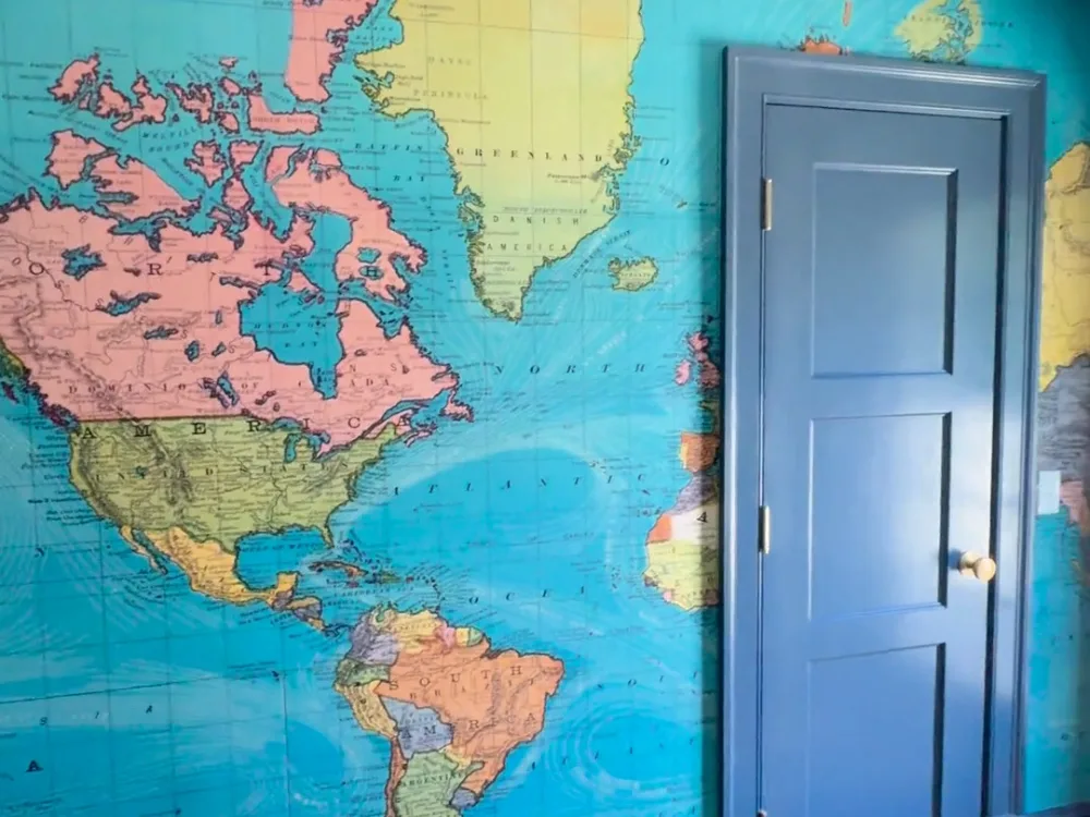 Wallpaper map installation with blue painted door and trims