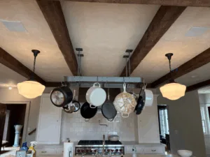 Interior paint restoration highlighting kitchen beams and hanging cookware.
