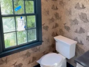 Detailed corner view of the powder room wallpaper installation featuring a delicate fish design above a white cabinet.